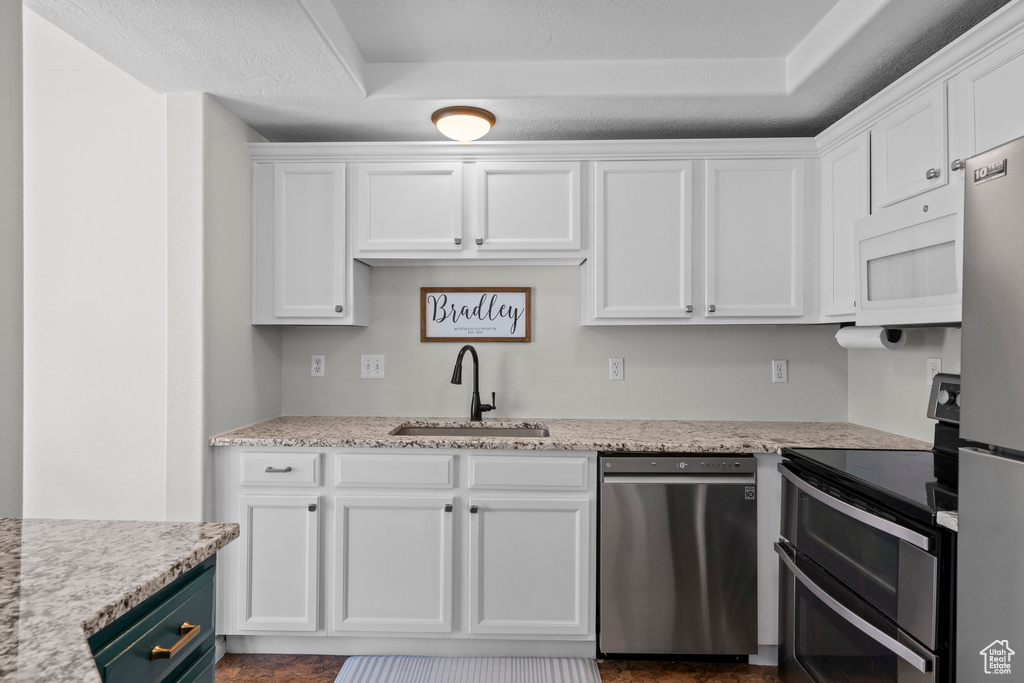 Kitchen with stainless steel appliances, a sink, and white cabinetry