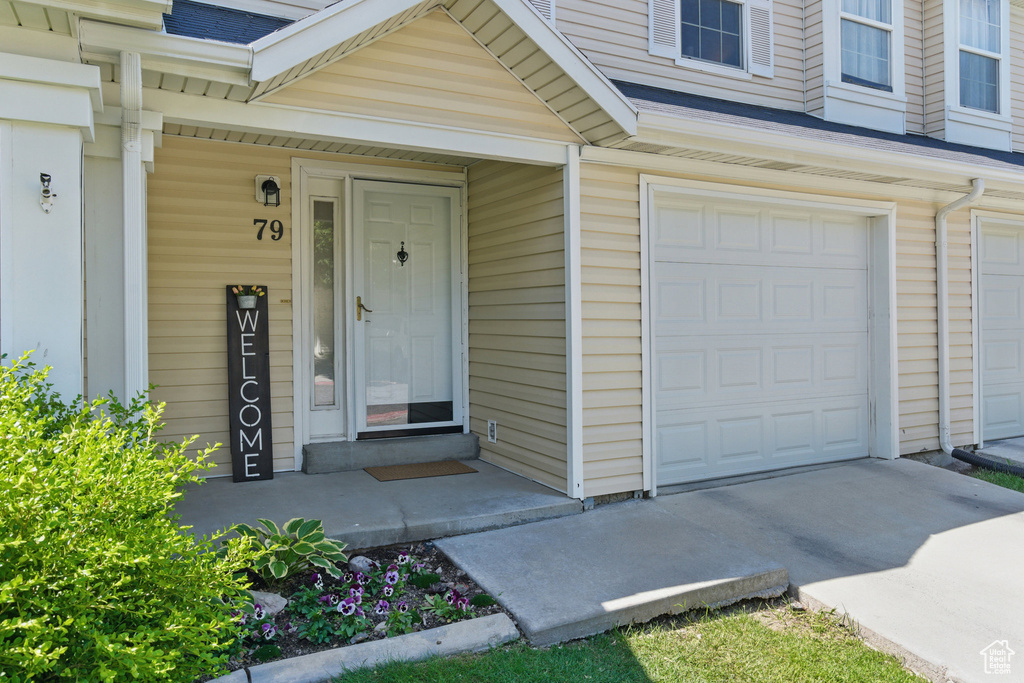 Doorway to property featuring an attached garage and concrete driveway