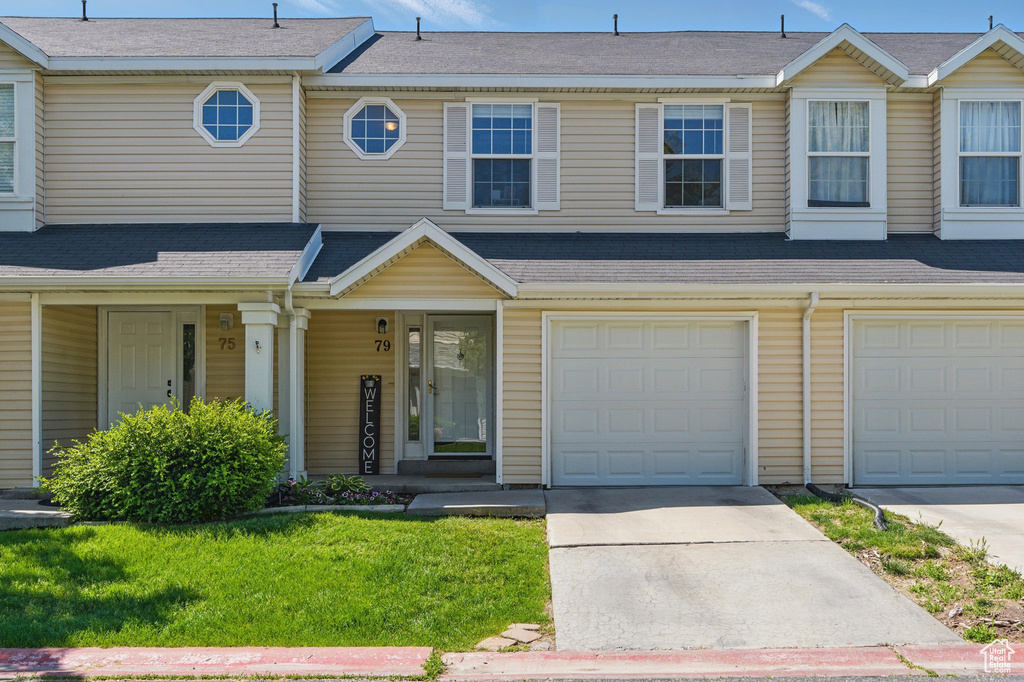 View of property featuring concrete driveway, an attached garage, a porch, and a front lawn