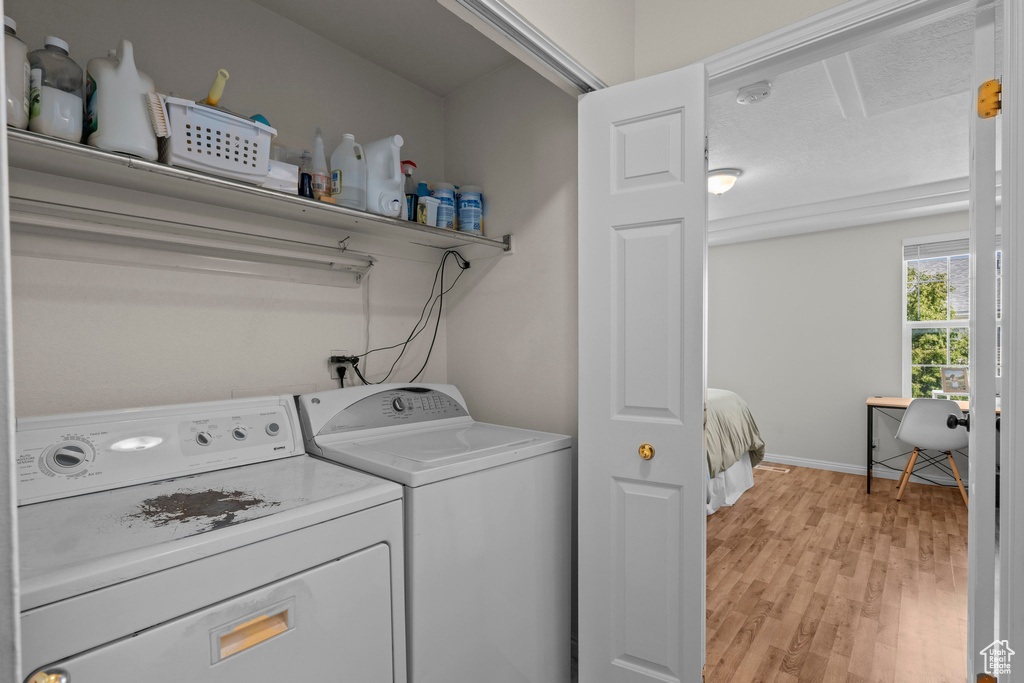 Washroom featuring washer and dryer, light wood-style flooring, and baseboards