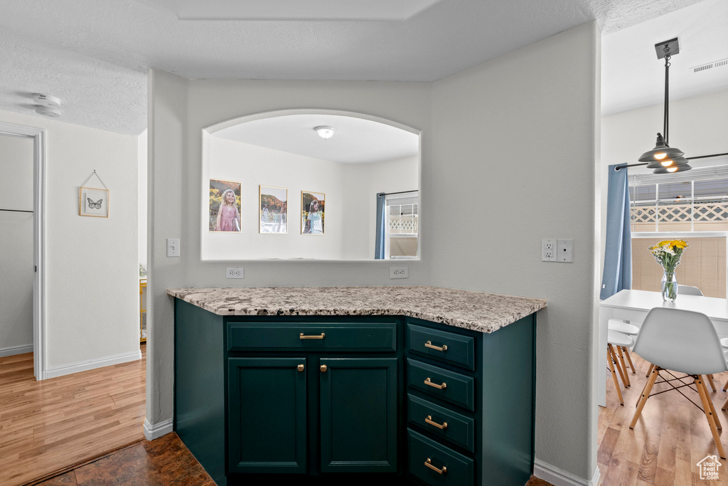 Kitchen featuring light countertops, light wood-style flooring, green cabinetry, and arched walkways