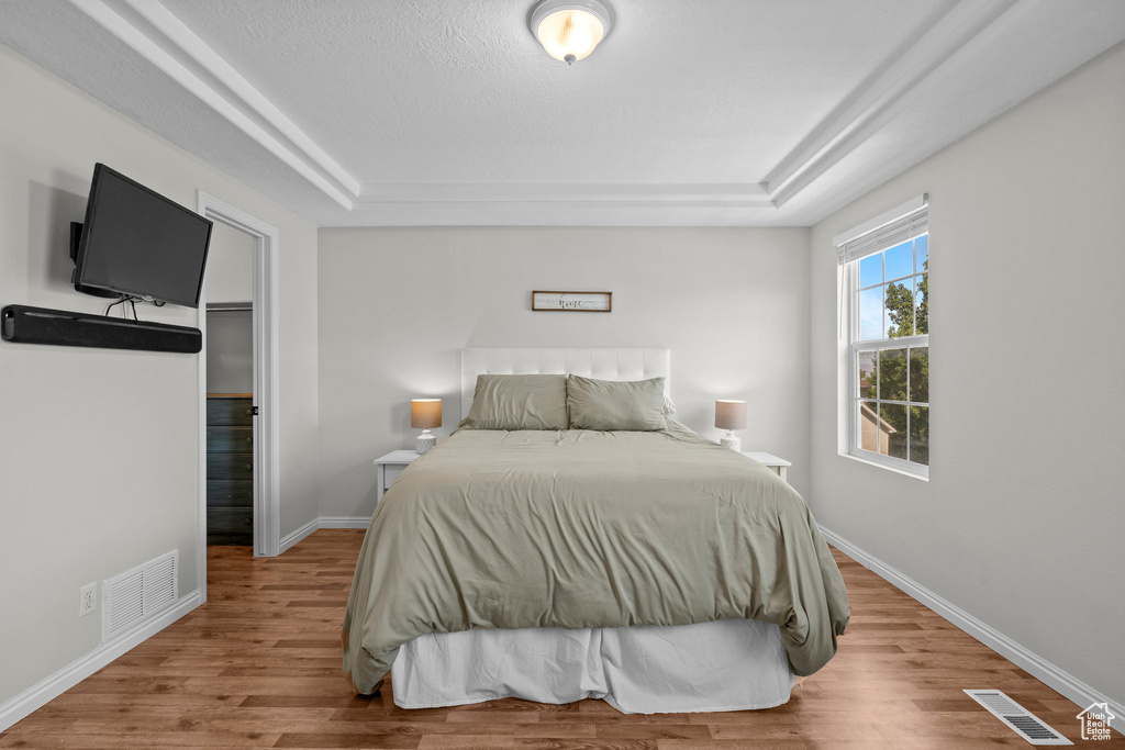 Bedroom featuring a tray ceiling, wood finished floors, and baseboards