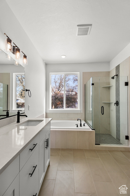 Full bathroom featuring vanity, a bath, a shower stall, and tile patterned floors