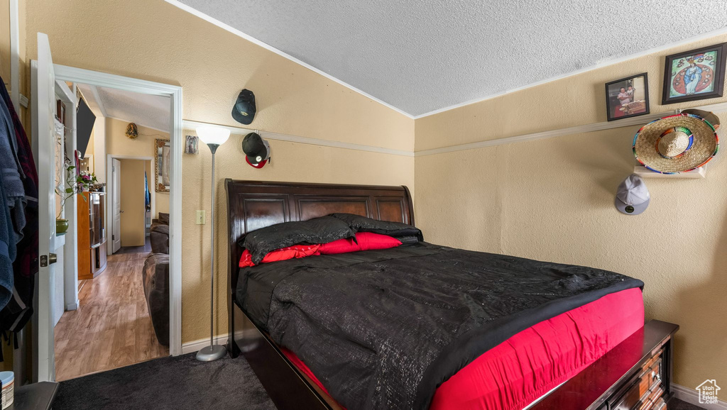 Bedroom with lofted ceiling, a textured ceiling, a textured wall, and baseboards
