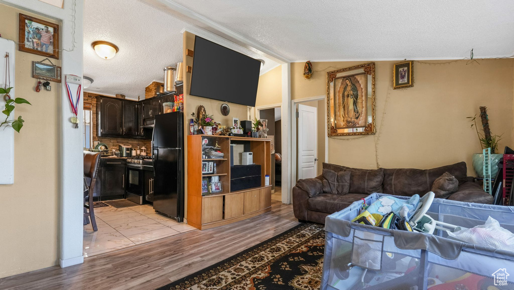 Living area with light wood finished floors, a textured ceiling, and lofted ceiling