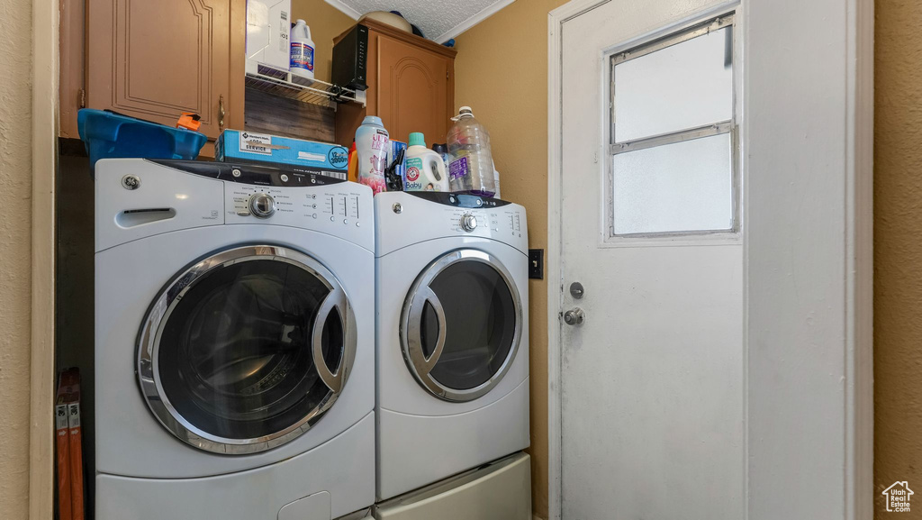 Laundry room featuring washing machine and dryer, cabinet space, and ornamental molding