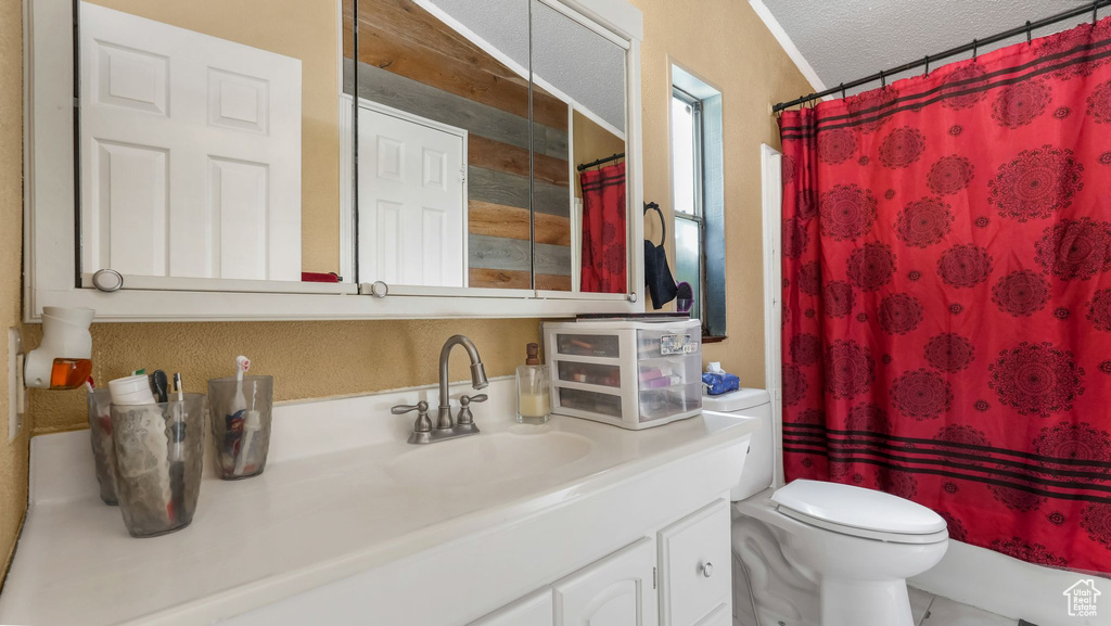 Bathroom featuring toilet, vanity, a textured ceiling, and curtained shower