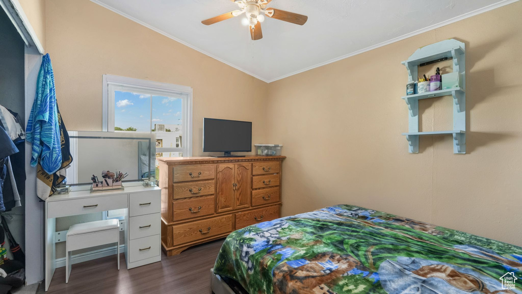 Bedroom featuring dark wood-type flooring, vaulted ceiling, crown molding, and ceiling fan