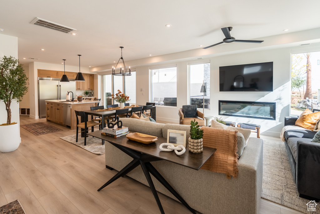Living area with recessed lighting, light wood finished floors, a chandelier, ceiling fan, and a premium fireplace