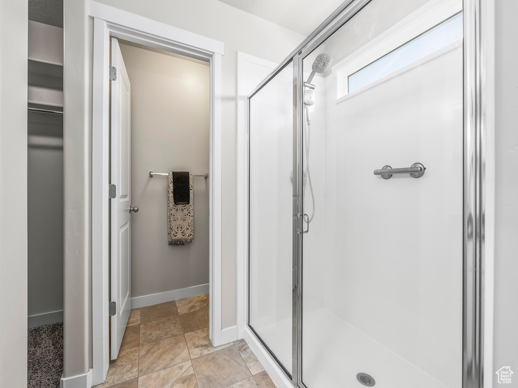 Full bathroom featuring a stall shower, a spacious closet, baseboards, and stone finish floors