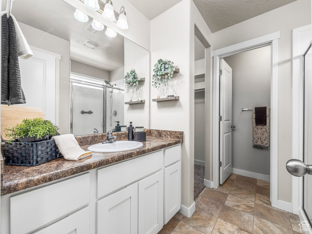Bathroom with a stall shower, vanity, baseboards, and a walk in closet