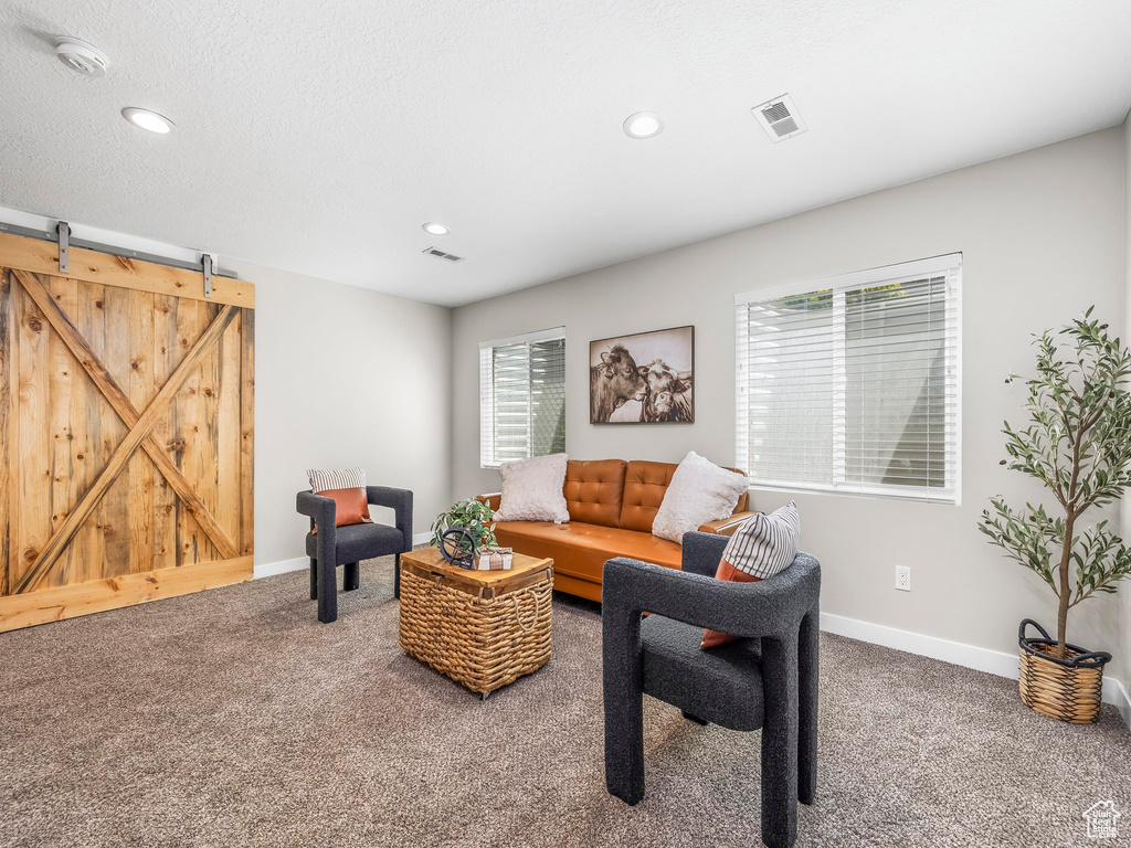 Carpeted living room featuring a barn door, recessed lighting, and baseboards