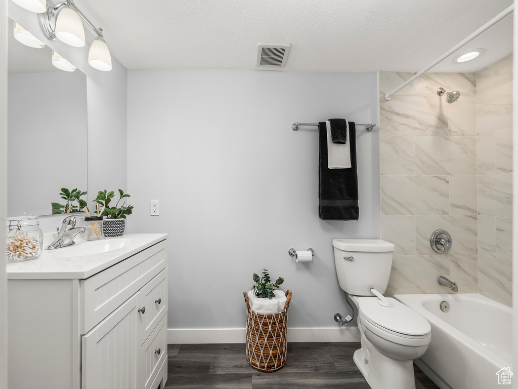 Full bathroom with toilet, vanity, baseboards, wood finished floors, and tub / shower combination