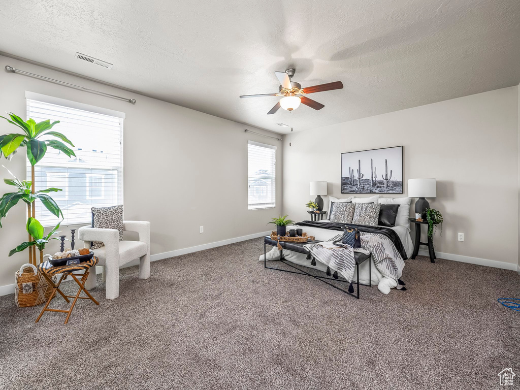 Carpeted bedroom with a textured ceiling, baseboards, and a ceiling fan