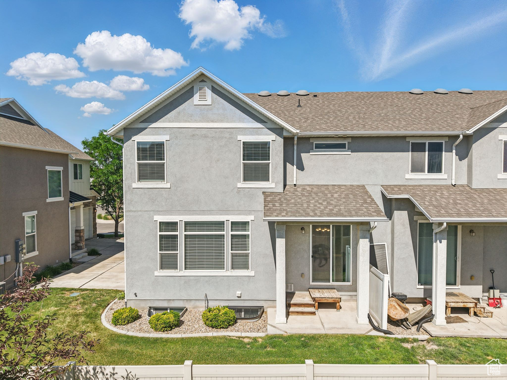 View of front of property with stucco siding, a shingled roof, and a patio