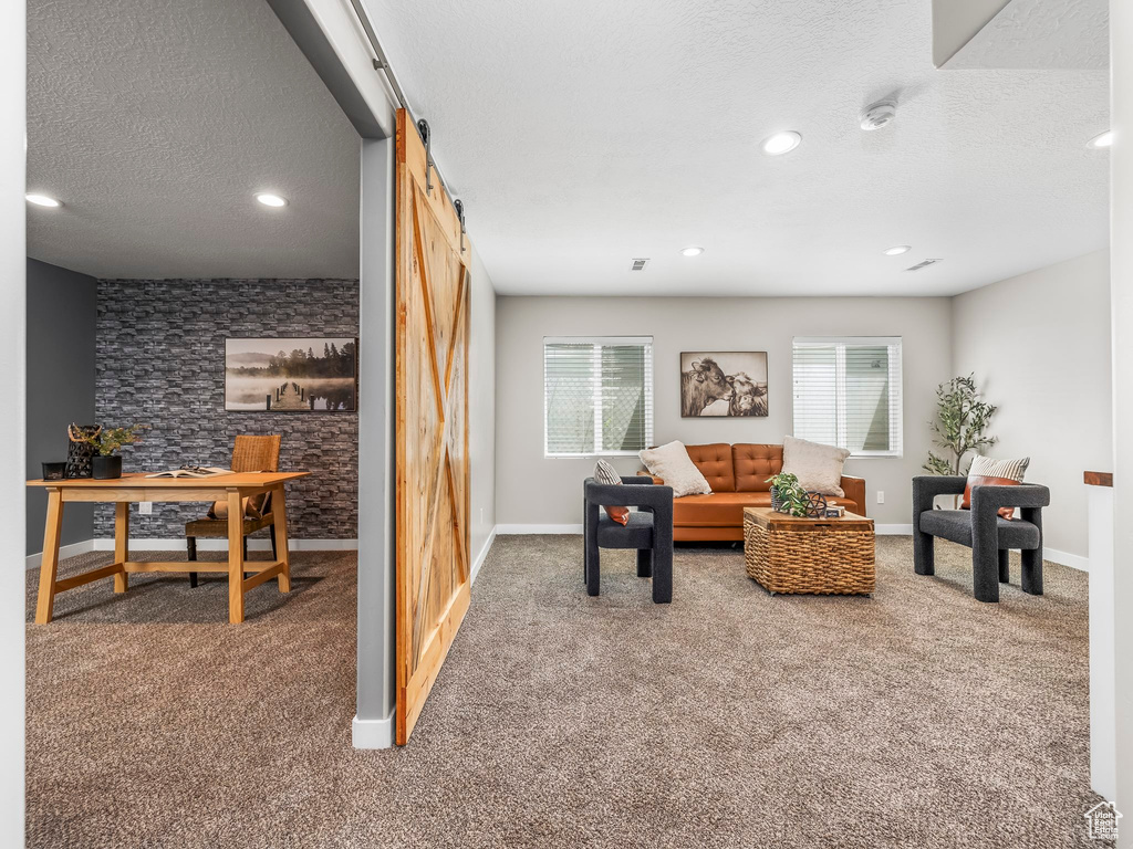 Carpeted living area with a barn door, plenty of natural light, a textured ceiling, baseboards, and recessed lighting