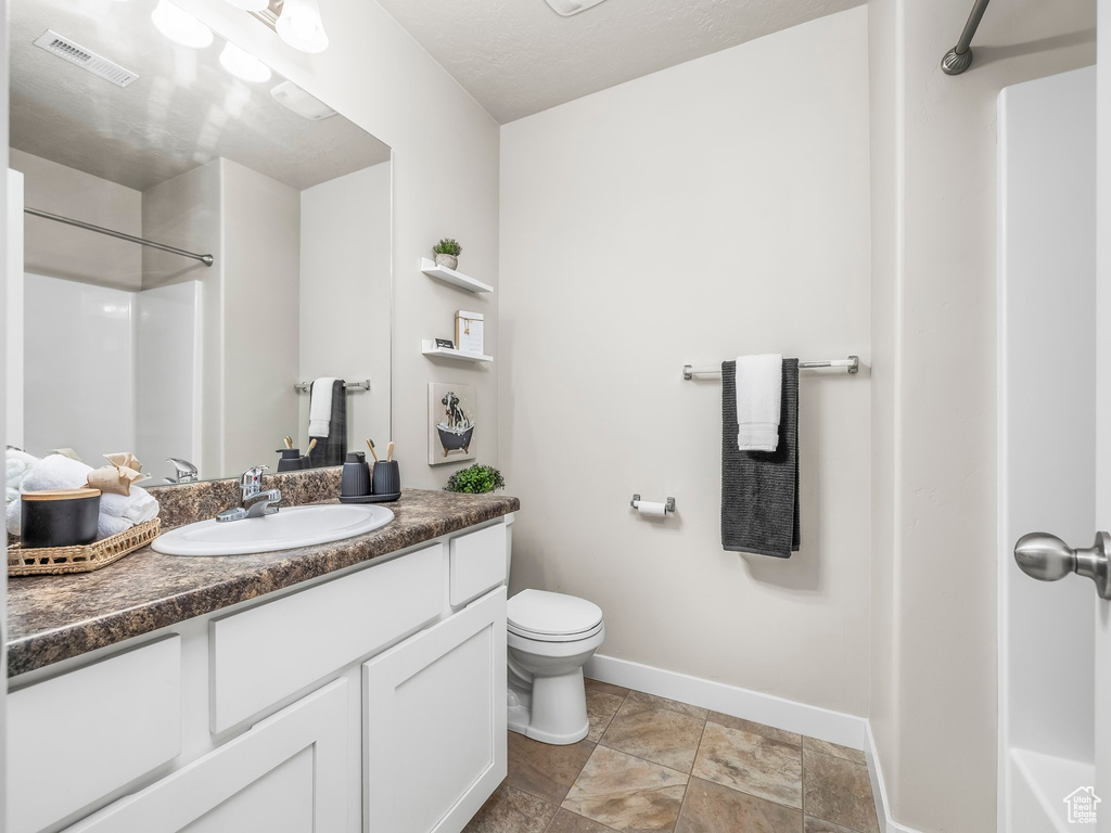 Bathroom with baseboards, vanity, a shower, and toilet