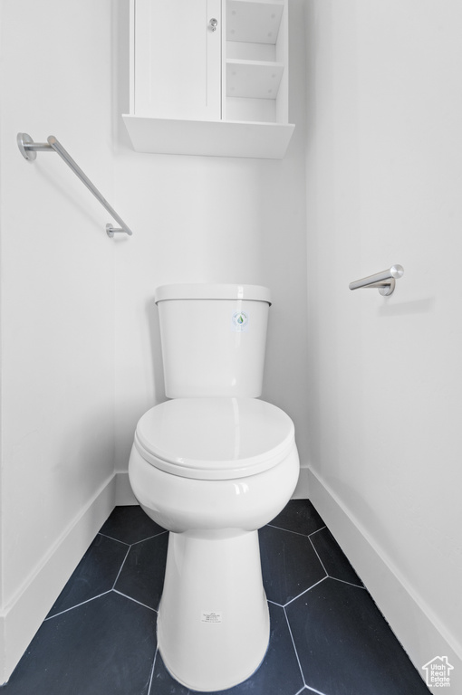 Bathroom with toilet, tile patterned flooring, and baseboards