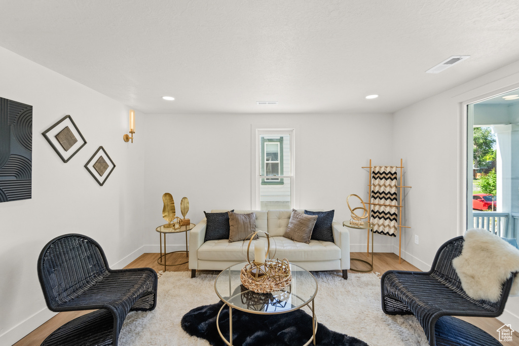 Living area with plenty of natural light, baseboards, wood finished floors, and recessed lighting