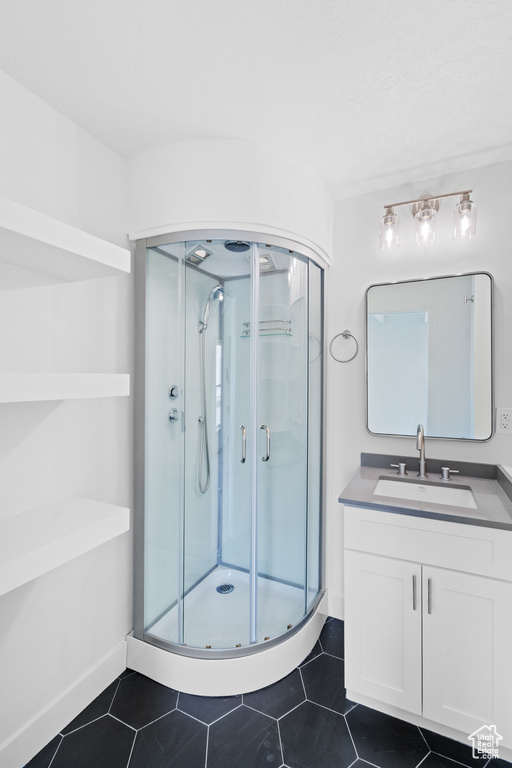 Full bath with a shower stall, tile patterned flooring, vanity, and baseboards