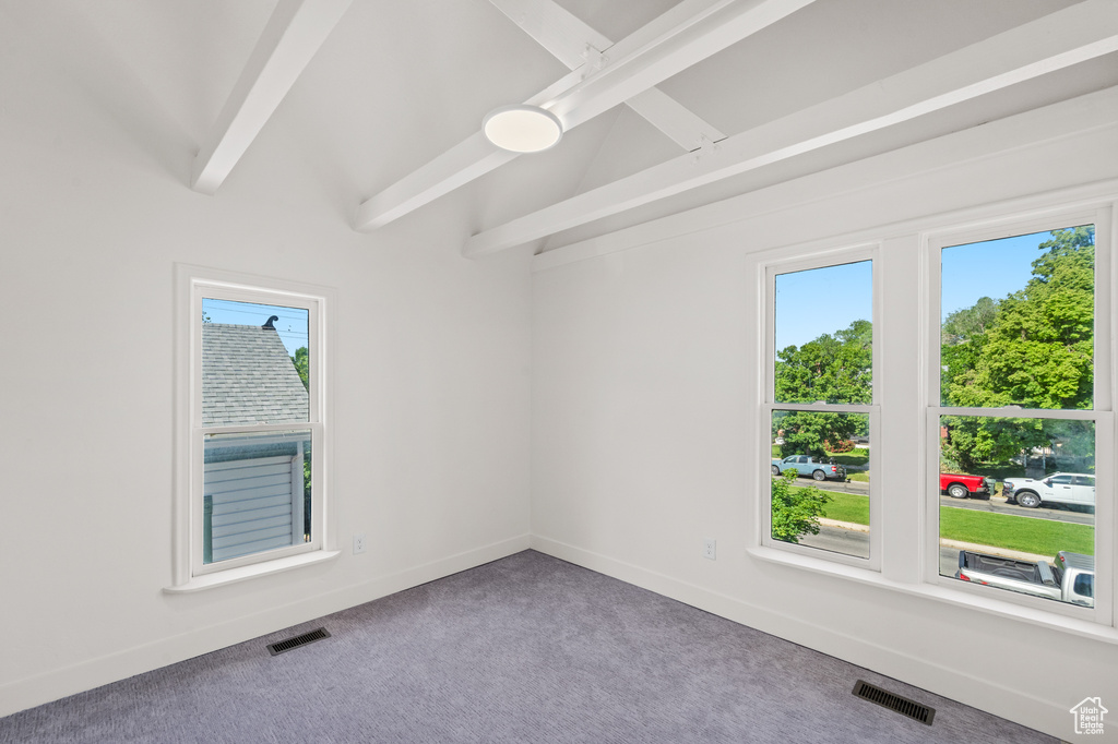 Carpeted spare room with plenty of natural light, baseboards, and beamed ceiling