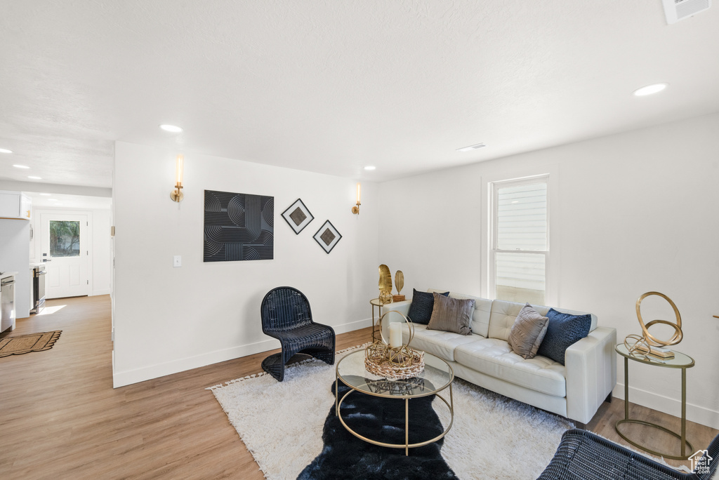 Living area with baseboards, light wood-style flooring, and recessed lighting