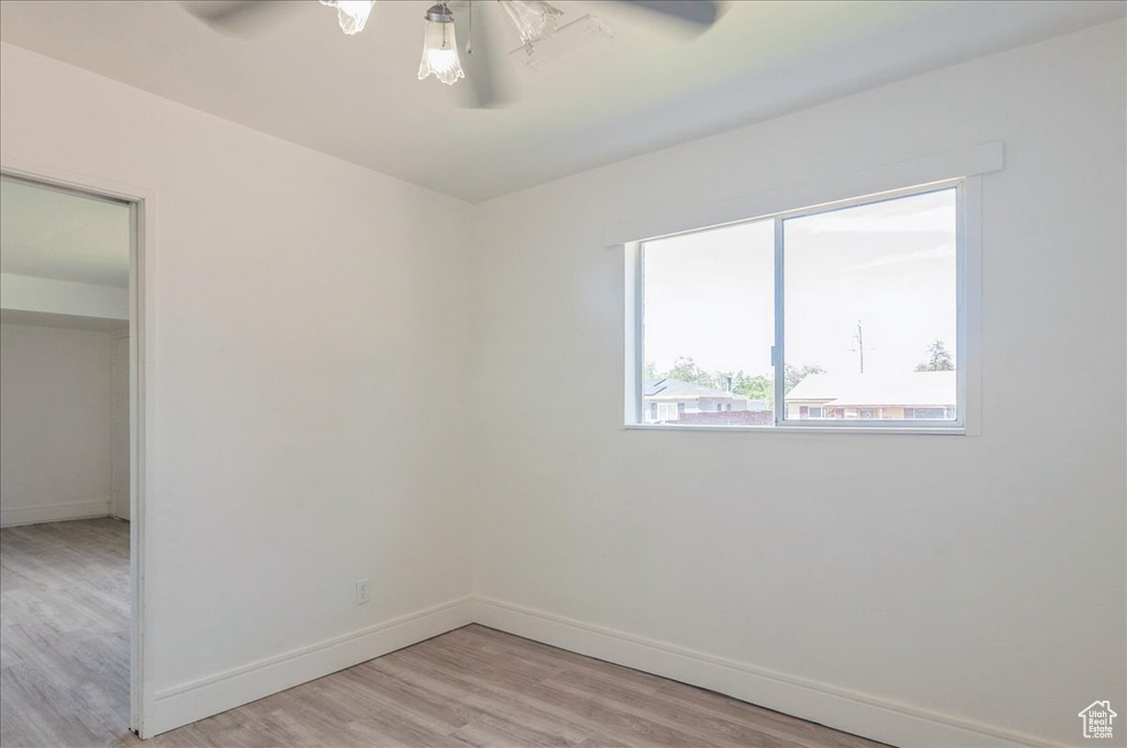 Spare room featuring a ceiling fan, light wood-style flooring, and baseboards