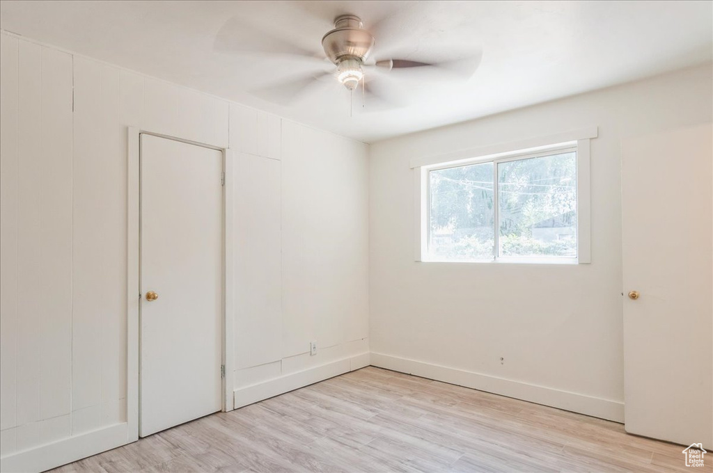 Unfurnished room featuring ceiling fan, light wood finished floors, and baseboards