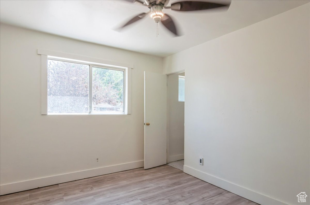 Empty room featuring a ceiling fan, baseboards, and light wood-style floors