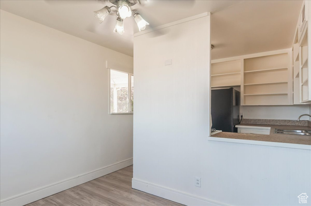 Kitchen featuring freestanding refrigerator, a sink, baseboards, wood finished floors, and a ceiling fan