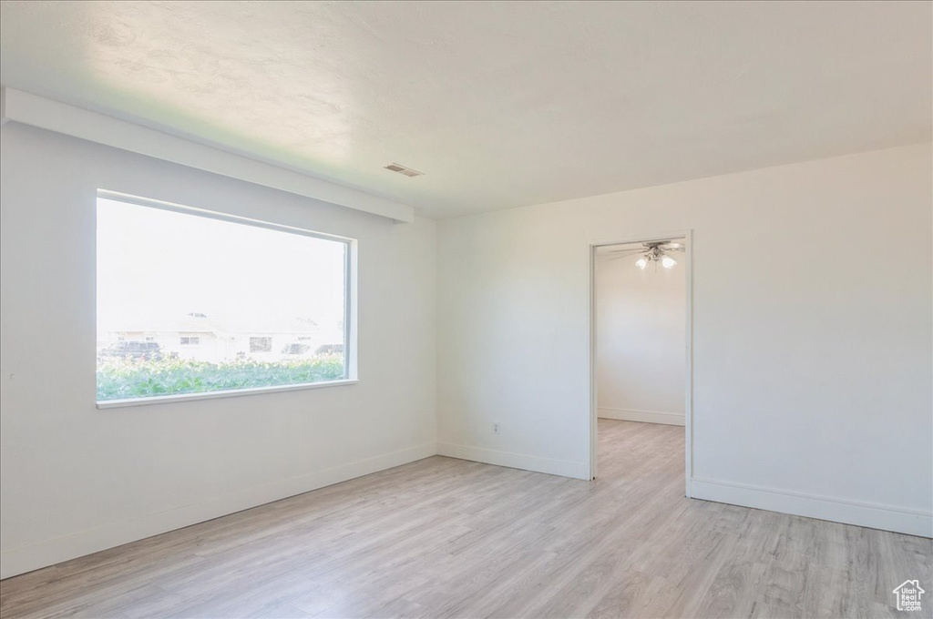 Empty room with light wood-style floors, baseboards, and ceiling fan