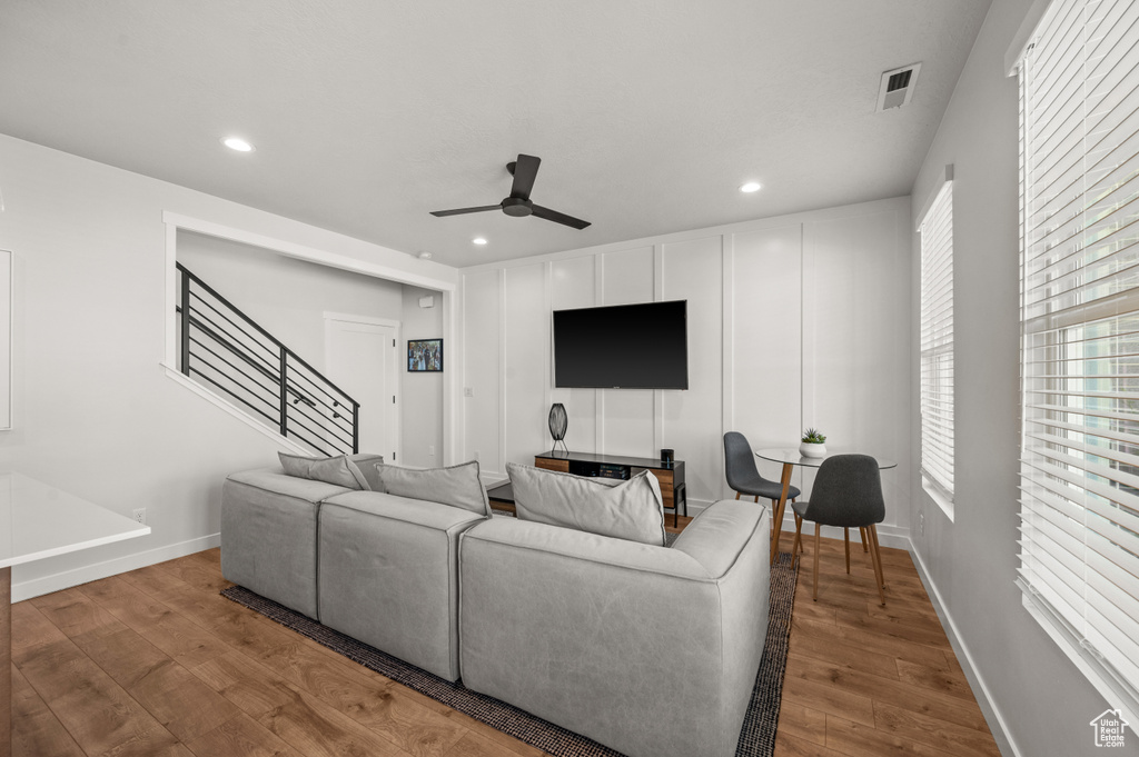 Living area with wood finished floors, ceiling fan, recessed lighting, stairway, and healthy amount of natural light