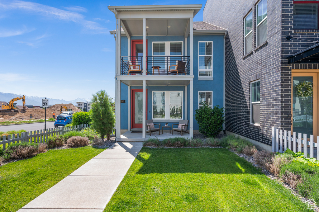 View of front of property featuring a mountain view, stucco siding, and a balcony