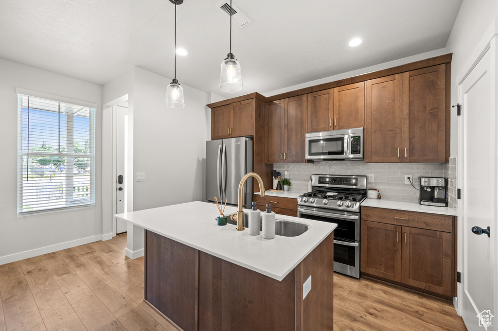 Kitchen with appliances with stainless steel finishes, a sink, decorative backsplash, baseboards, and light countertops