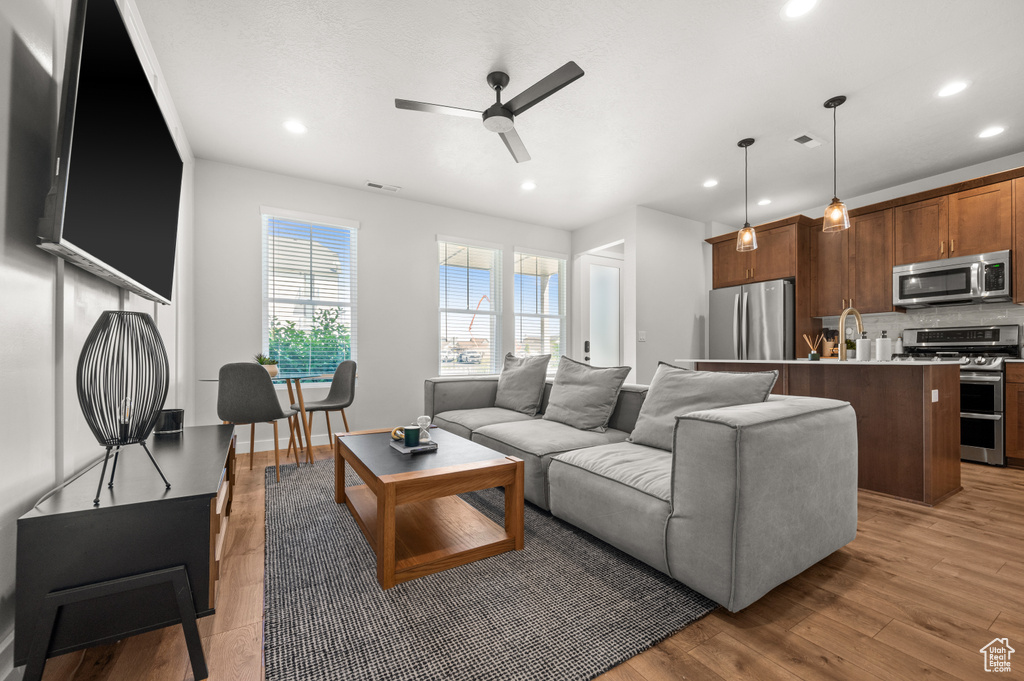 Living area with a ceiling fan, recessed lighting, and light wood finished floors