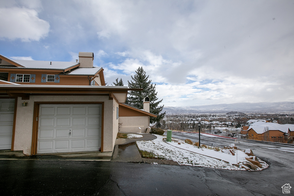 Snow covered property with a chimney, stucco siding, and a mountain view