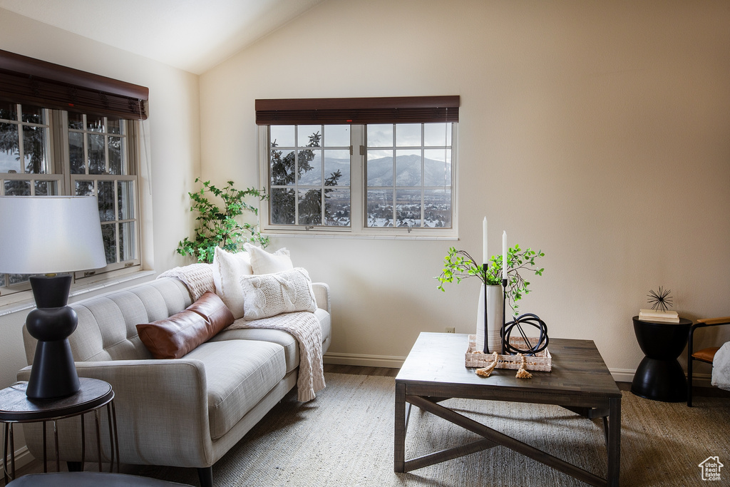 Living area with vaulted ceiling, baseboards, and wood finished floors