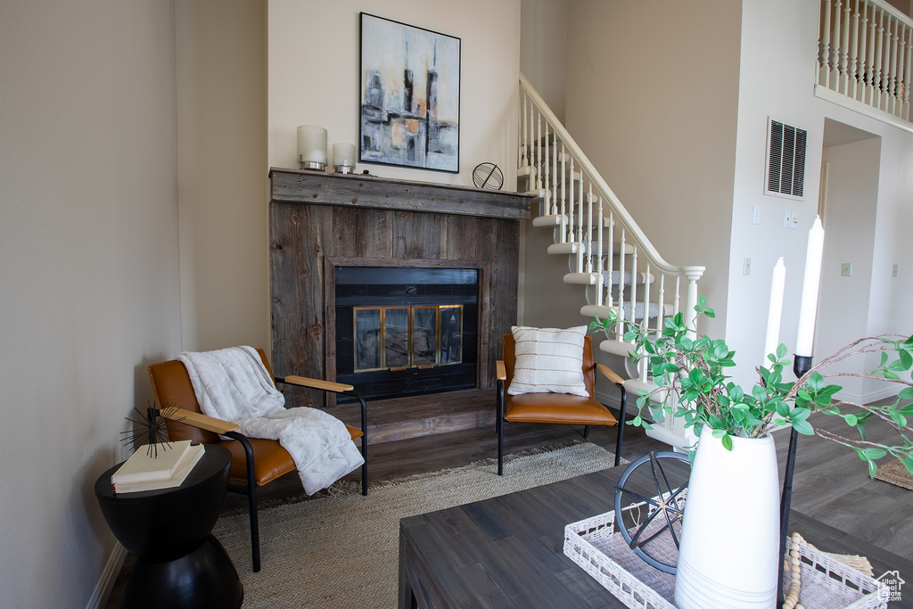 Living area with wood finished floors, a glass covered fireplace, and stairway