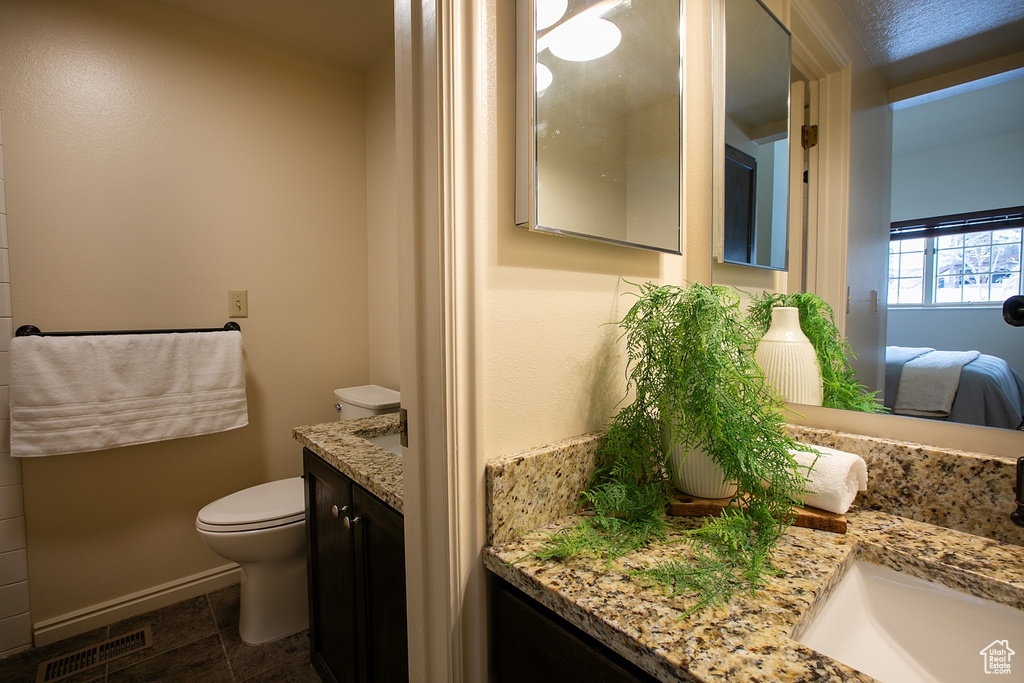 Bathroom featuring vanity, toilet, ensuite bath, and baseboards
