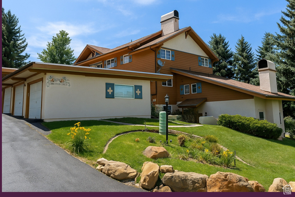View of side of home with a chimney, a lawn, and stucco siding