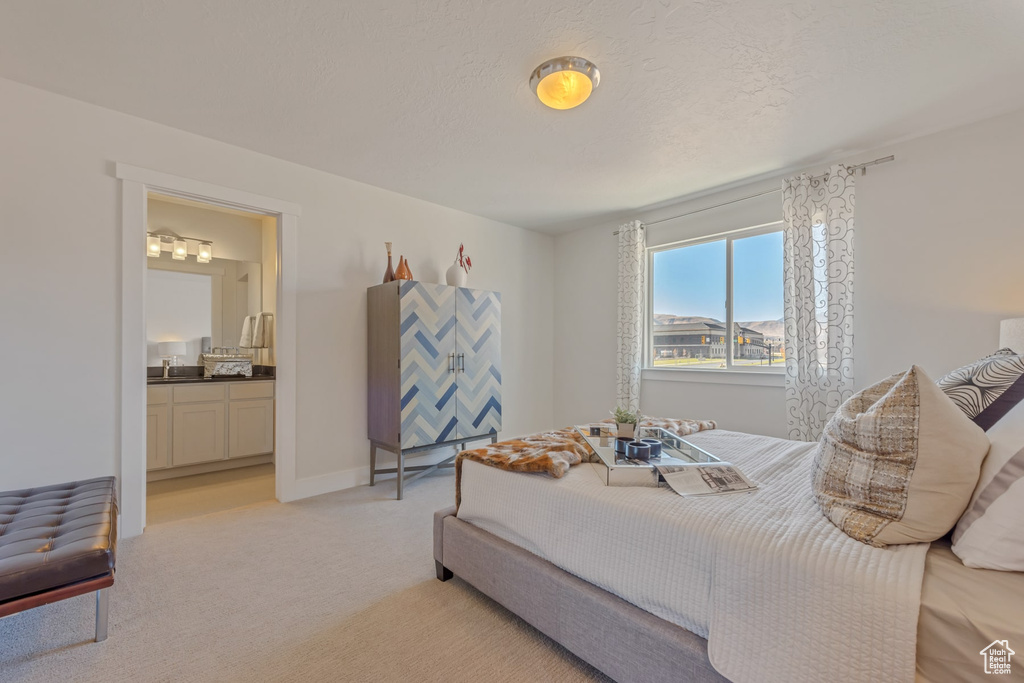Bedroom featuring light colored carpet, ensuite bathroom, and baseboards