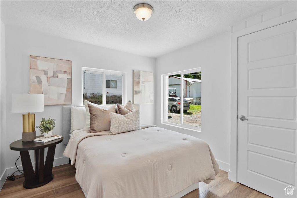 Bedroom featuring light wood-type flooring, a textured ceiling, and baseboards