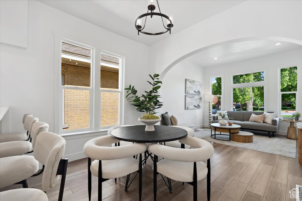 Dining area featuring arched walkways, light wood-type flooring, a chandelier, and recessed lighting