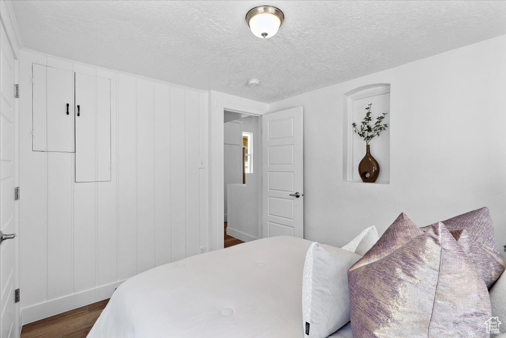 Bedroom with dark wood finished floors, a textured ceiling, and baseboards