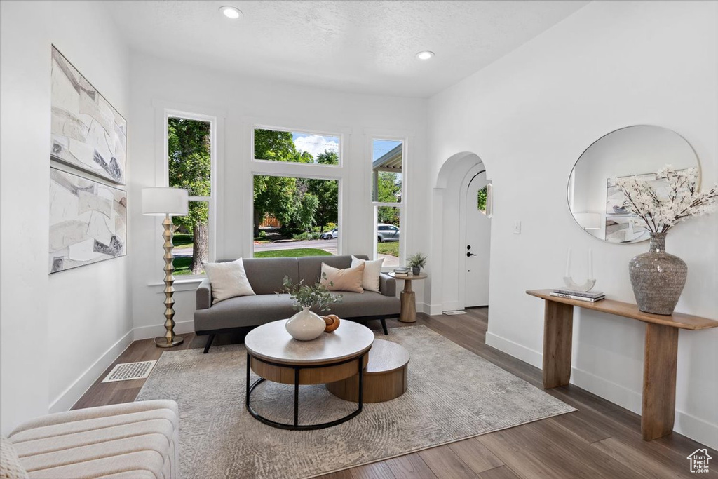 Living area with arched walkways, recessed lighting, baseboards, and wood finished floors