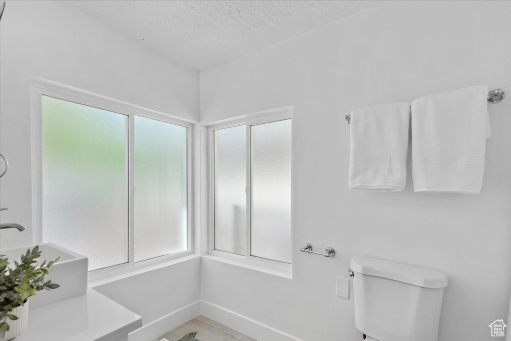 Bathroom featuring a textured ceiling, toilet, and baseboards