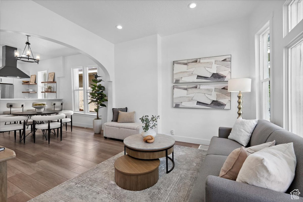 Living room with arched walkways, wood finished floors, recessed lighting, a chandelier, and baseboards