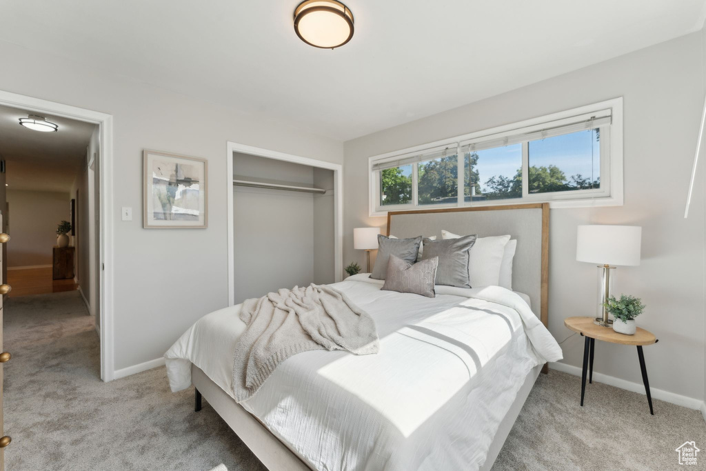 Bedroom featuring light carpet, a closet, and baseboards