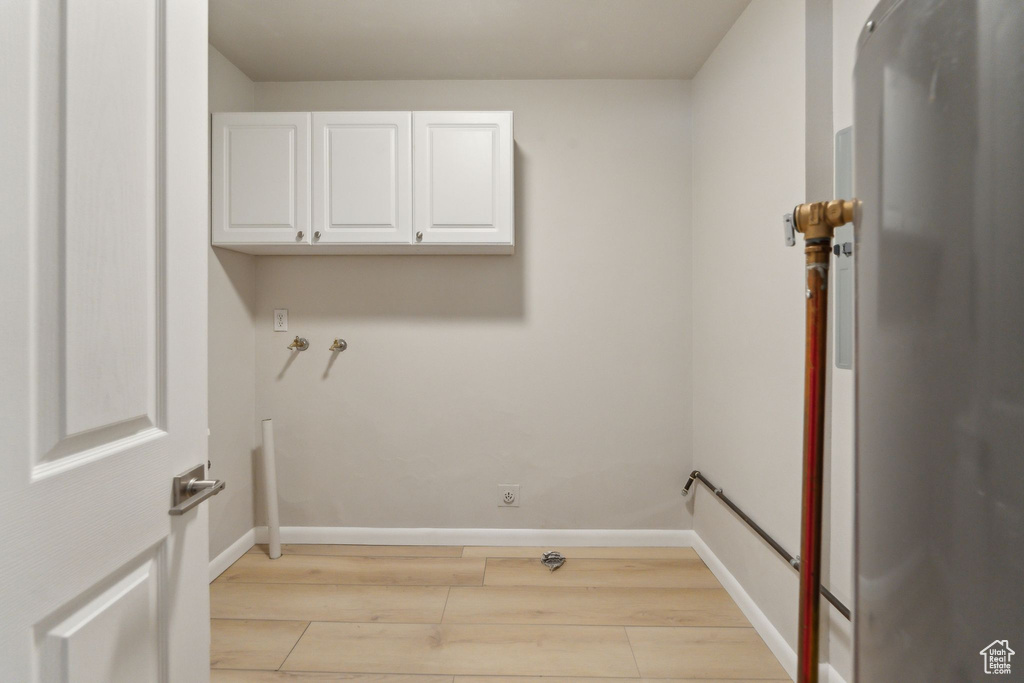 Laundry area featuring cabinet space, light wood-type flooring, baseboards, and washer hookup