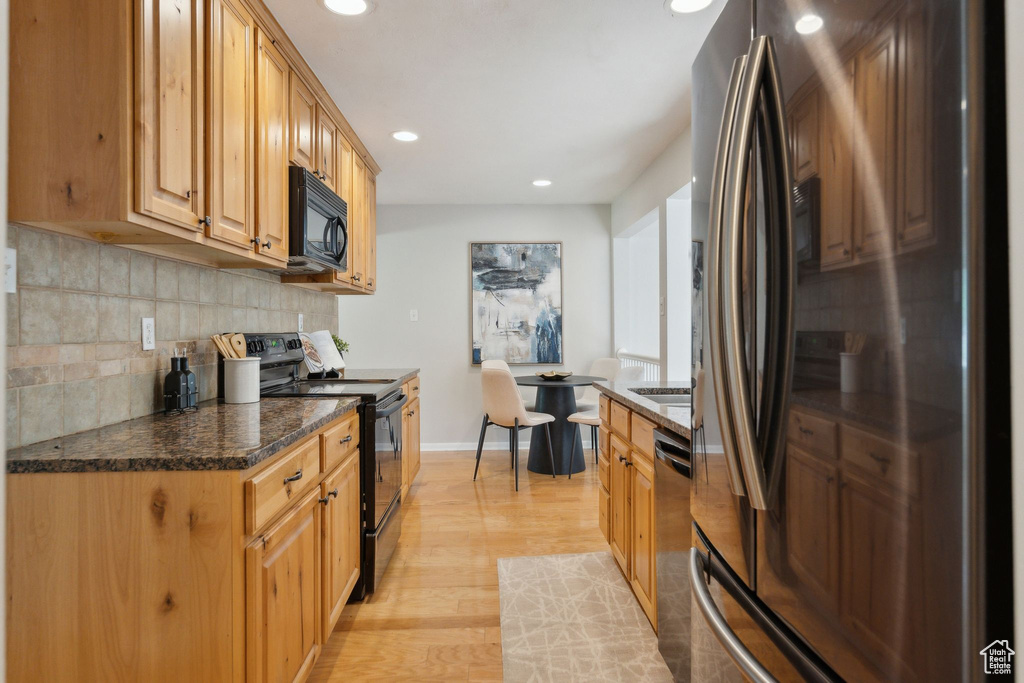 Kitchen featuring black appliances, light wood-style flooring, recessed lighting, tasteful backsplash, and baseboards